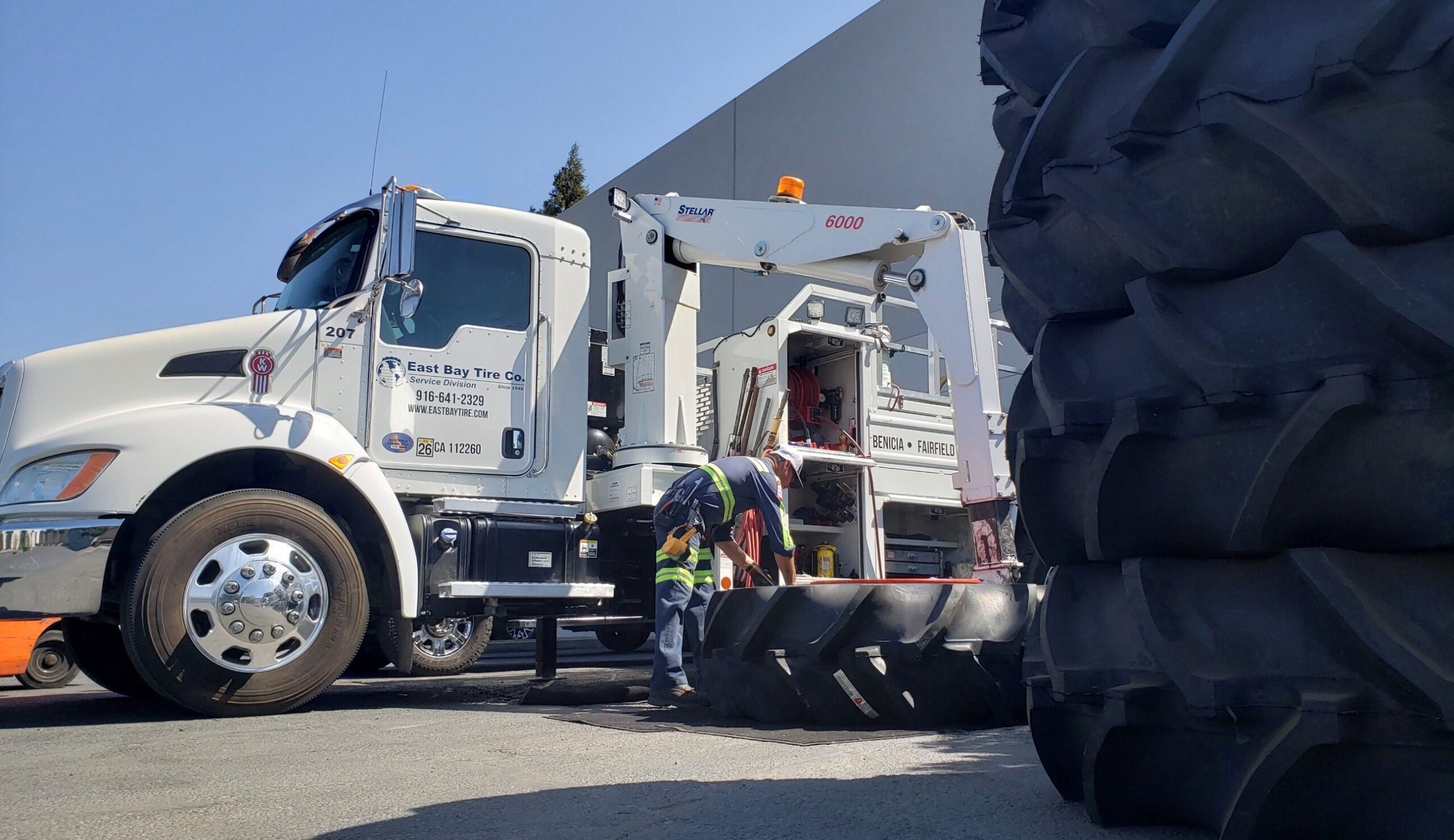 East Bay Tire camión con grandes neumáticos apilados cerca de