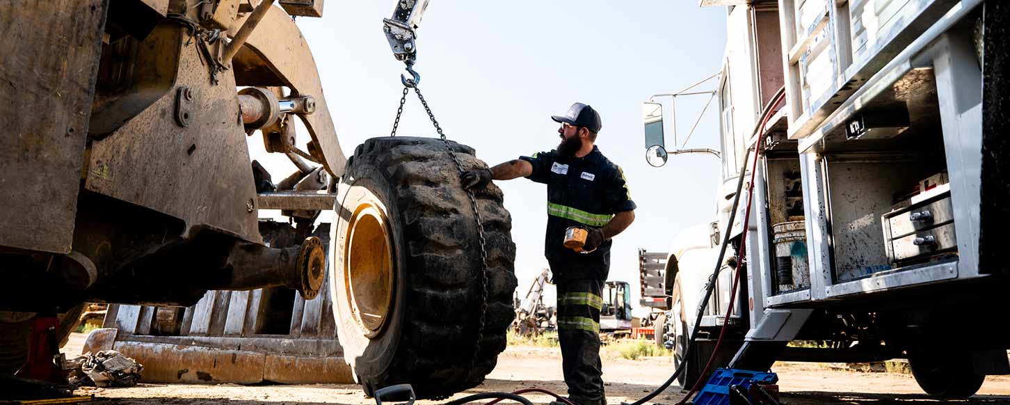 East Bay Tire employee helps lift a large tire