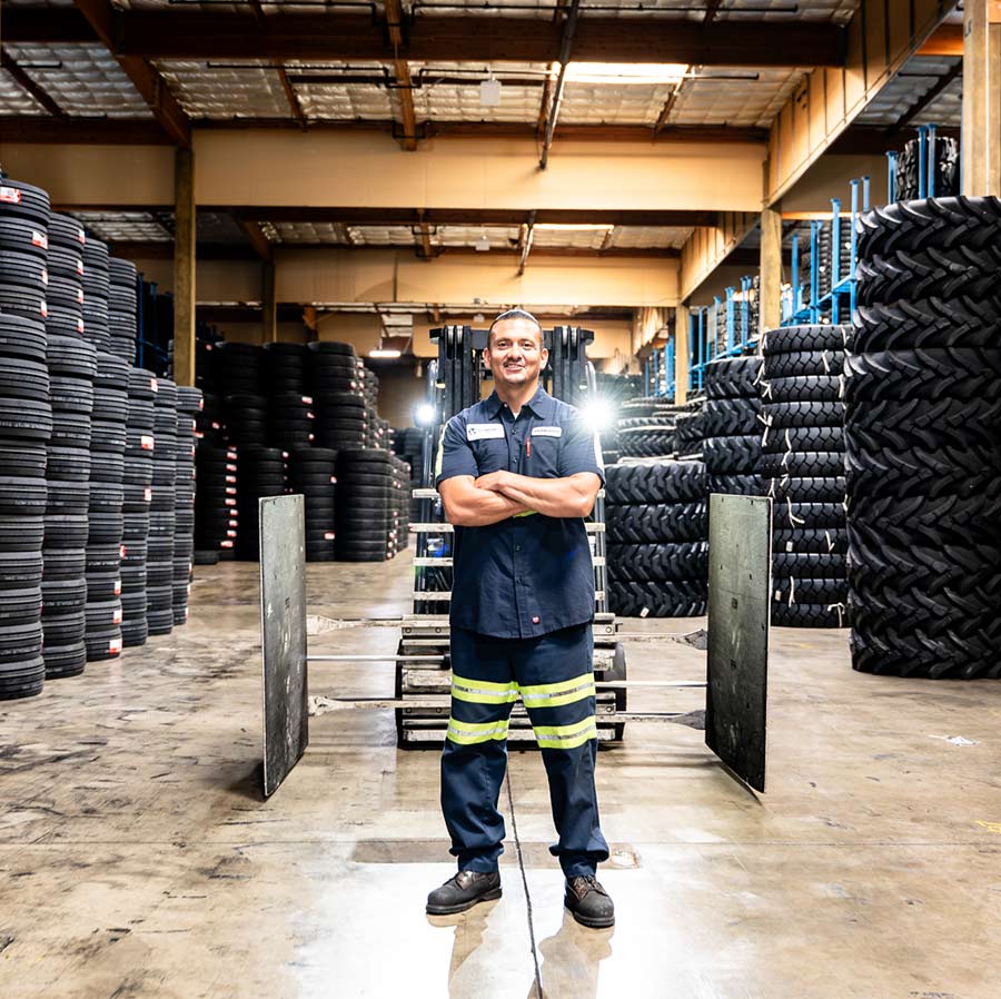Un empleado de EBT entre pilas de neumáticos OTR de gran tamaño en las instalaciones de East Bay Tire.
