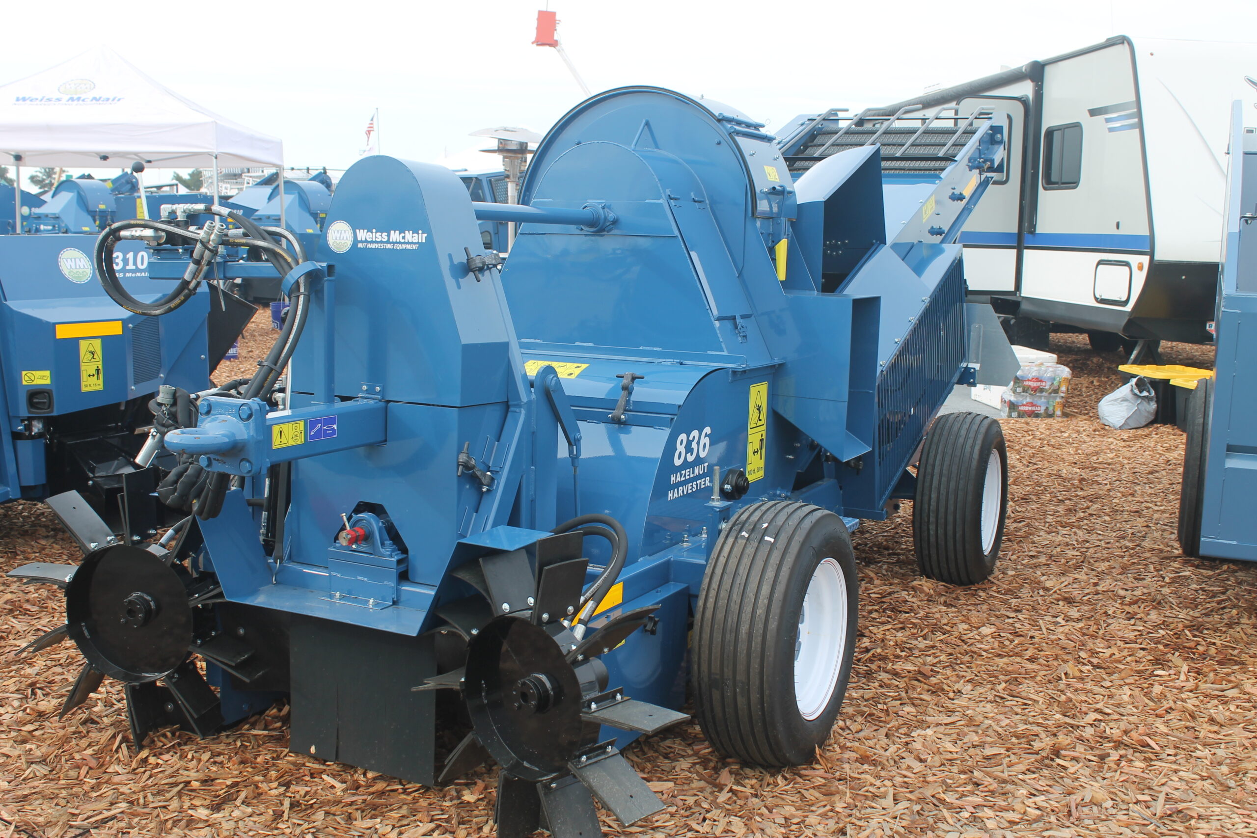 A blue East Bay Tire harvester sits atop wood chips