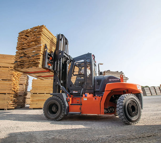 Forklift lifting pallets of lumber